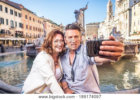 Senior couple at Navona square Rome - Happy tourists visiting italian famous landmarks
