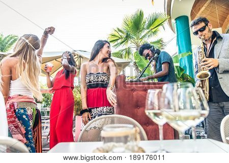 Multiethnic group of friends making party in a lounge bar - Cheerful young adults having fun and celebrating outdoors