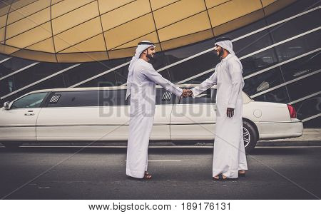 Arabic businessmen in Dubai handshaking with limousine in the background