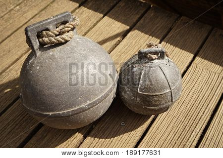 Two old fishing net metal balls on wooden floor