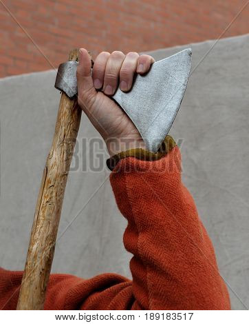 Hand of man leaning on old battle broadaxe.Hand is bent in elbow. Vikings widely used such weapon.