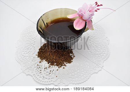one pink flower fuchsia and black instant coffee in a small Cup on a white napkin