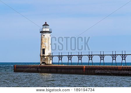 The Lighthouse at Manistee Michigan with its elevated catwalk approach is situated upon a breakwater that extends into Lake Michigan.