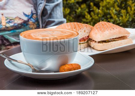 Coffee art and panini at outdoor cafe.
