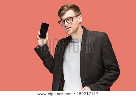 The young caucasian businessman in glasses on red studio background talking on cell phone