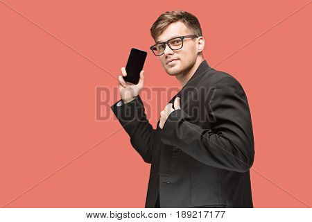 The young caucasian businessman in glasses on red studio background talking on cell phone