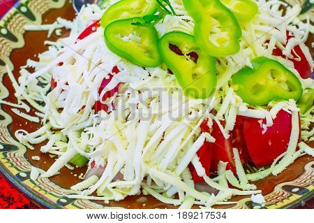 Bulgarian traditional Bulgarian Shopsky Salad or Shopska salata made of tomatoes, cucumbers and cheese on the bulgarian red tablecloth