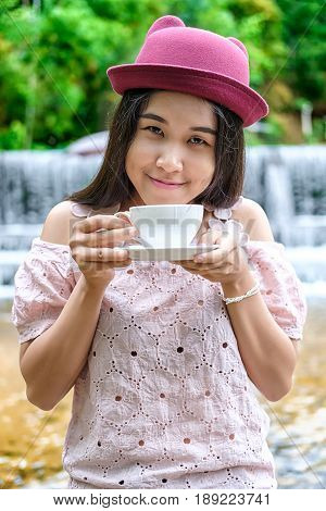 Asian woman relaxing on couch with coffee at water fall cafe.Close up