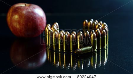 9mm bullets and a red apple on the black mirror background