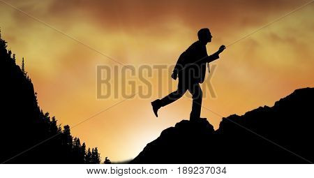 Digital composite of Silhouette businessman walking on mountain during sunset
