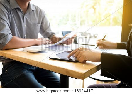 Teamwork process Two business colleague meeting to discussing the new project business strategy plan with using digital tablet and calculator. Briefing brainstorming consulting.