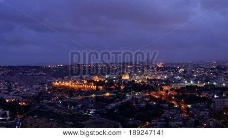 Night falls on Jerusalem city. Citylights light up at night while sunset goes over Jerusalem Dome of the Rock and Al Aqsa mosque.