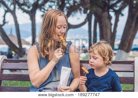 Mom And Son Eat Fried Sweet Potatoes In The Park. Junk Food Concept