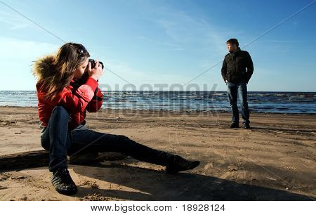 Mladá žena s fotografii svého přítele na pláži (žena v zaměření)