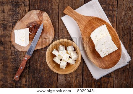 Sliced fresh brined white cheese from cow milk on wooden table. Top view.