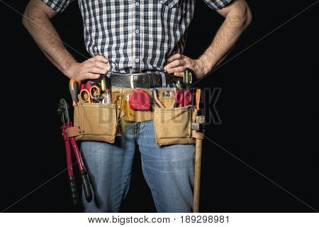 detail of handyman with leather toolsbelt and tools on dark background