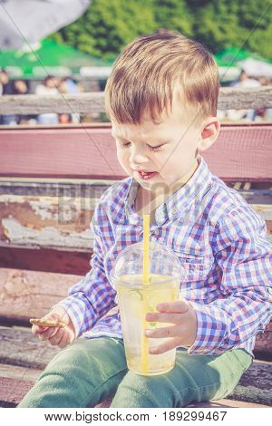 Two years old boy frowned when he tasted a bitter lemon seed while drinking lemonade. Poor quality food street food concept