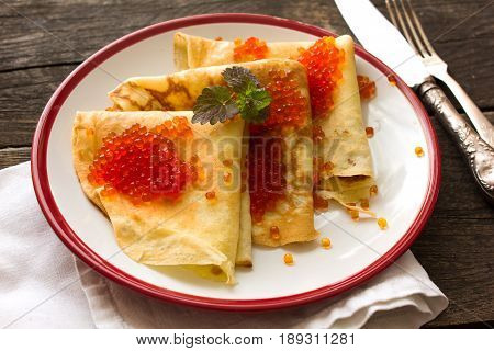 Stack of thin crepes (blini) with red caviar for breakfast. overhead view. russian food