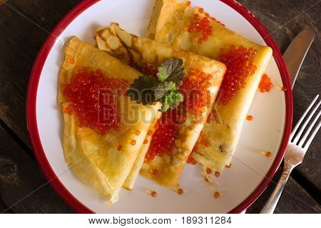 Stack of thin crepes (blini) with red caviar for breakfast. overhead view. russian food
