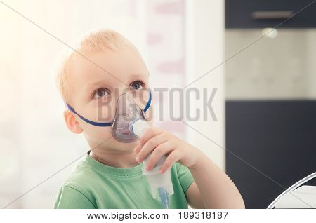 Boy making inhalation with nebulizer at home. child asthma inhaler inhalation nebulizer steam sick cough concept