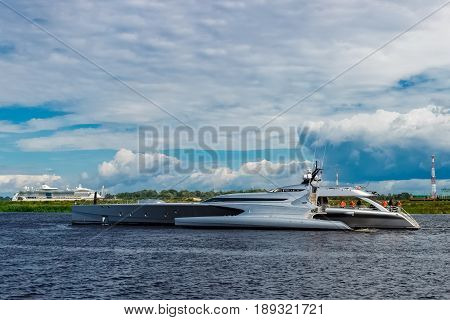 Large silver trimaran. Luxury yacht sailing by the river in Riga