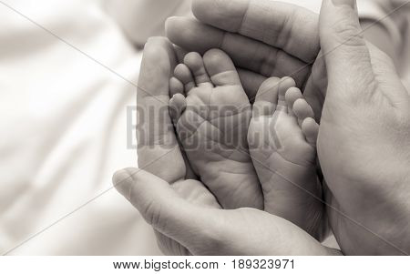 hands holding babies feet the shot is  monochromatic