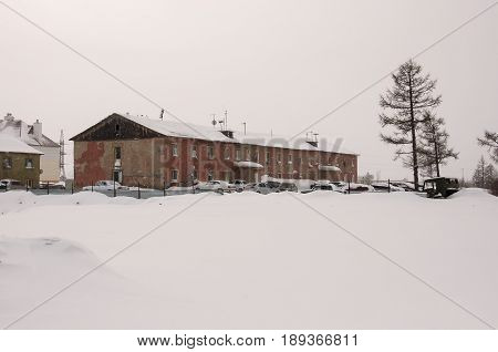 New Urengoy, YaNAO, North of Russia. February 02, 2013. Old two-storied  red house in winter with snow, cars and trees on the yard. Poverty and misery, North