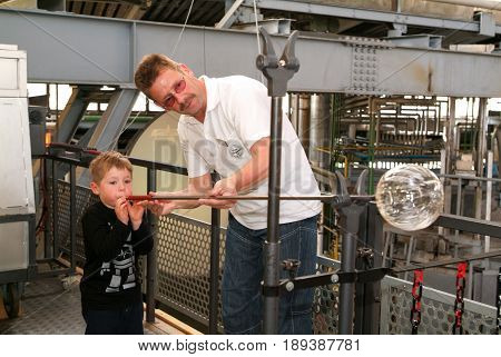 Boy Blowing Into Tube To Make A Glass