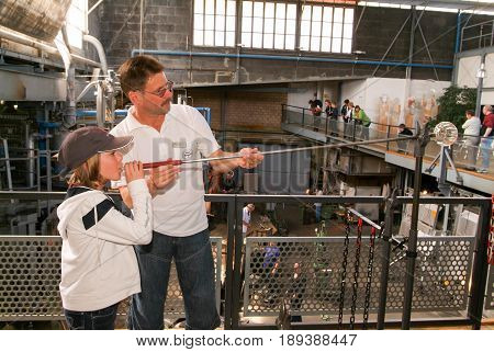 Girl Blowing Into Tube To Make A Glass