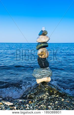 Colorful zen balancing rocks with blue sea background