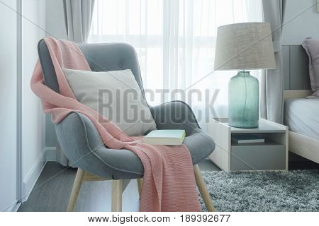 Gray Easy Armchair With Pink Scarf, Pillow And Book Next To Bed In The Bedroom