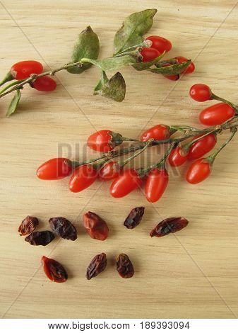 Fresh and dried goji berries on wooden board