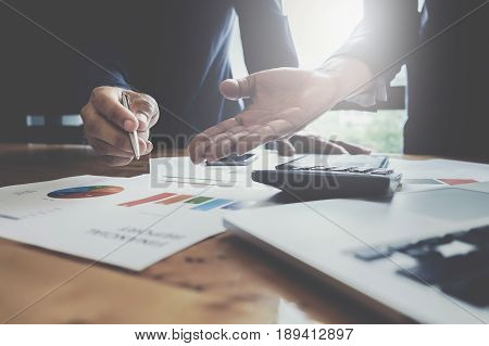 Businessman pointing graph chart with pathner for analyze plans in this mounth. vintage tone.