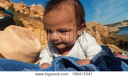 two months old baby boy laying on stomach on rocki beach