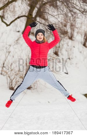 Outdoor sport exercising sporty outfit ideas. Woman wearing warm sportswear training exercising outside during winter jumping out of joy.