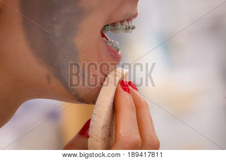 Woman Removing Mud Facial Mask With Sponge