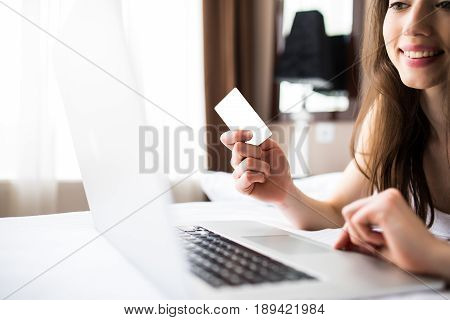 Woman Smiling And Looking In Front Of Her As She Uses Her Credit Card With Her Laptop.
