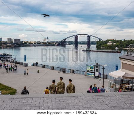 May 25 2017 Kiev Ukraine: three soldiers are walking along Poshtova Square. Kiev cityscape with a view of the Dnieper River.