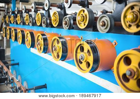 Rotating rubberized wheels of the winding machine. A lot of rotating wheels are yellow.