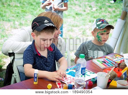 Zaporizhia/Ukraine- May 28, 2017: Charity Family festival:  art and craft activity, boy cocentrated on work at drawing workshop outdoors