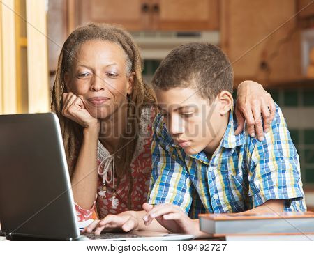 Mother And Teen Son Work In Kitchen On Laptop