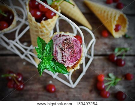 homemade ice cream cherries and chocolate in a waffle cone, fresh cherries on old wooden table - top view on the right