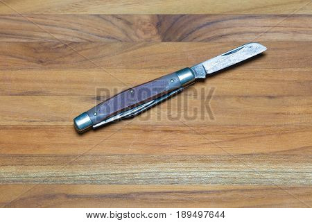 A utility knife with multiple blades lies open on a wood background