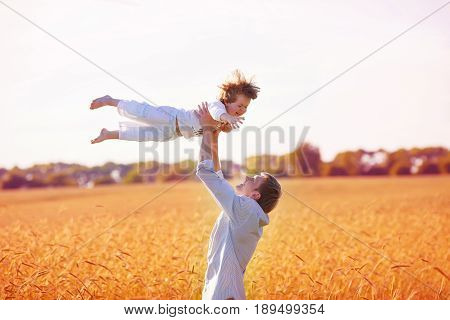 father lobbed her happy son who closed his eyes on the yellow wheat field among spikelets