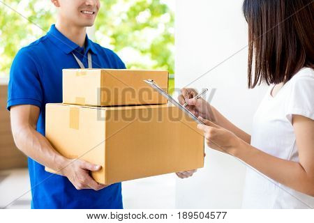 Woman signing document receiving parcel box from delivery man - courier service concept