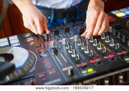 clever skillful DJ sets up his console with amany buttons and control knobs to play music