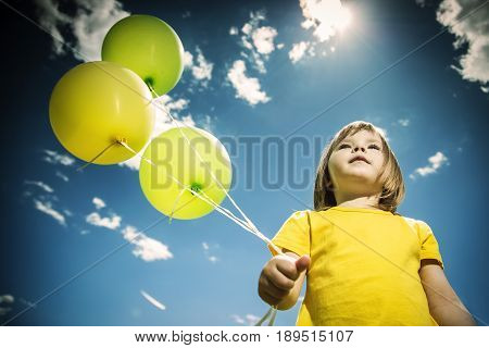 Cheerful little girl with colorful balloons. Summer sunny day.