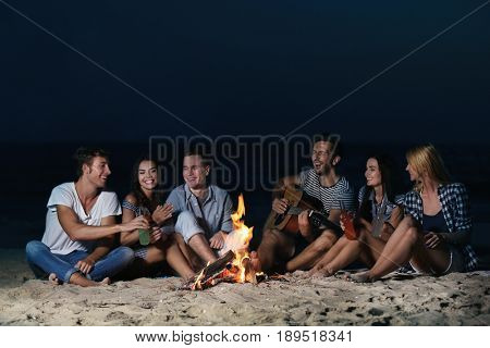 Happy friends near fireplace on the beach