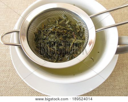 Loose green sencha tea in tea strainer