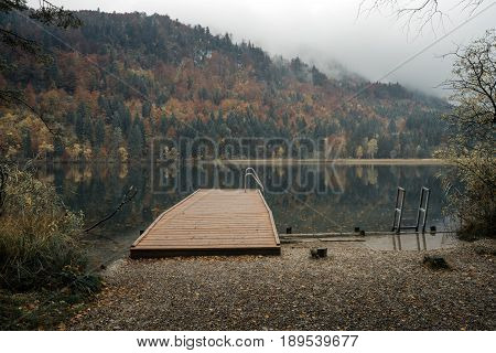 Fussen Bavaria Germany. Alpine Lake Schwansee near Hohenschwangau Castle and Neuschwanstein Castle. Cloudy autumn with rain. Autumn forest and beautiful view of the lake.